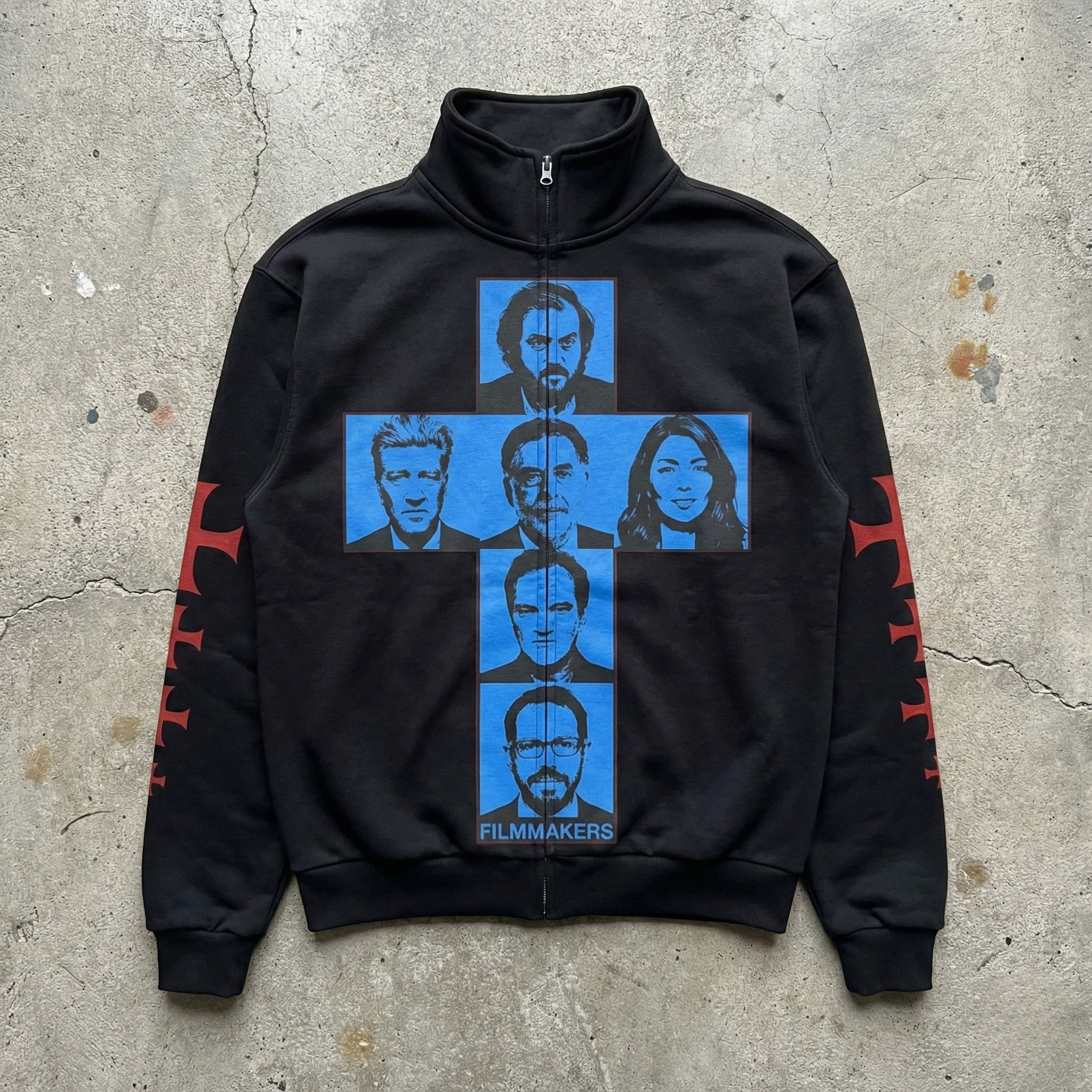 Black zip-up hoodie with blue graphic design on a concrete surface