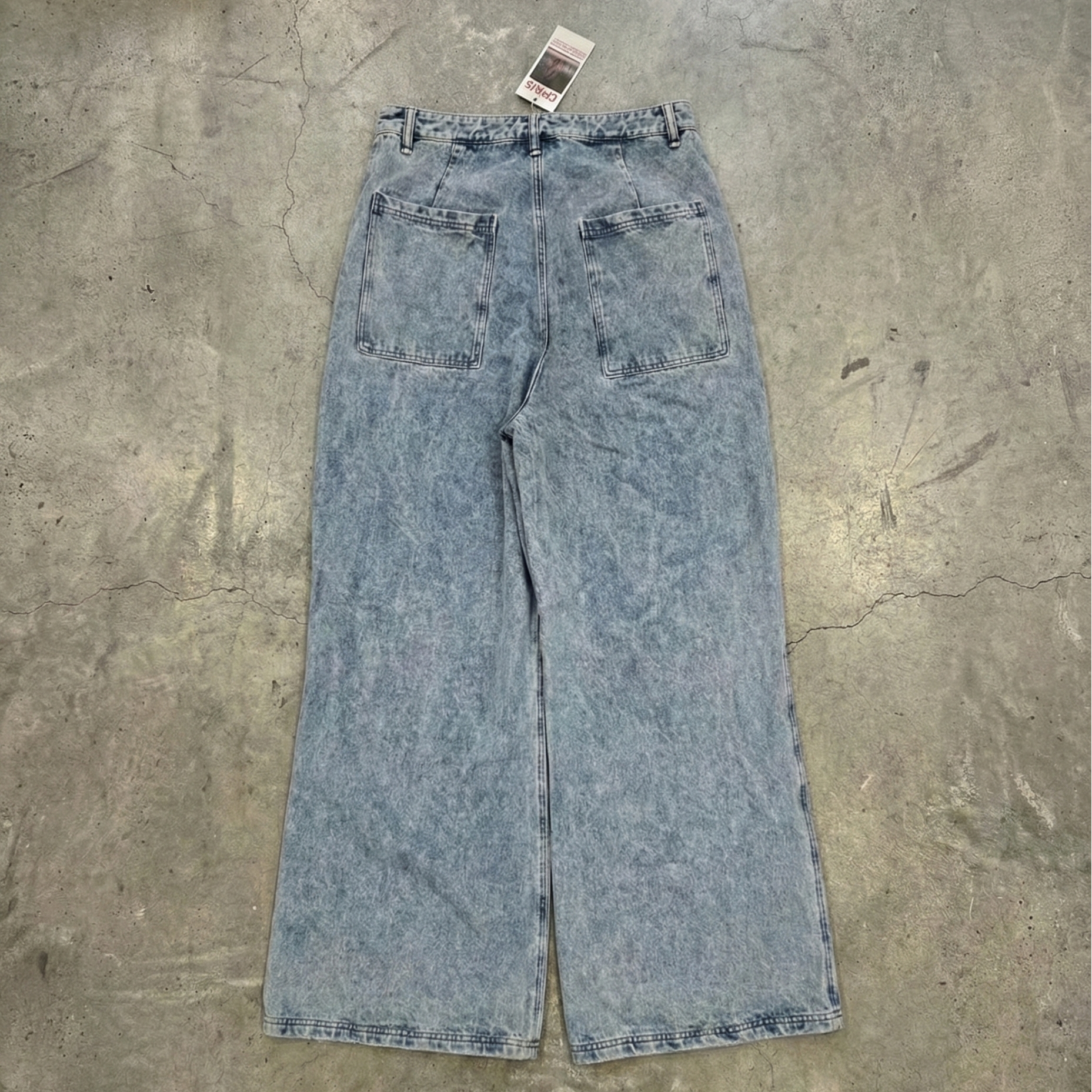 Blue acid-wash jeans on a textured gray surface